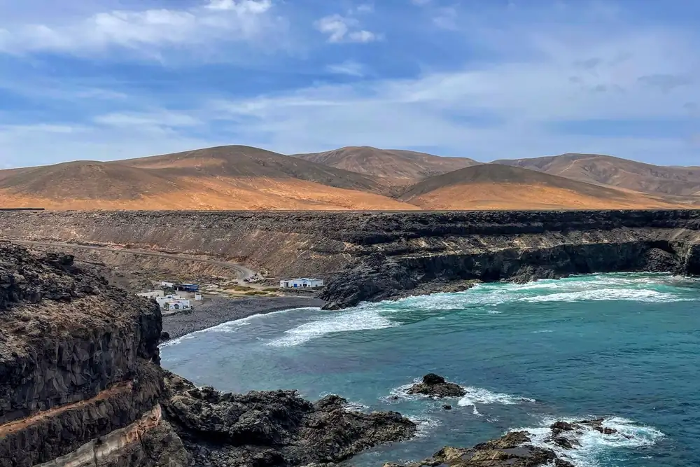 Turquoise zee en rotsige kust van Fuerteventura met bruine bergen op de achtergrond