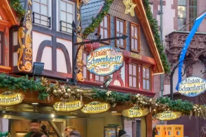 Versierd kraampje op een Duitse kerstmarkt met vakwerkgevel, groene slingers en lichtjes