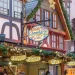 Versierd kraampje op een Duitse kerstmarkt met vakwerkgevel, groene slingers en lichtjes
