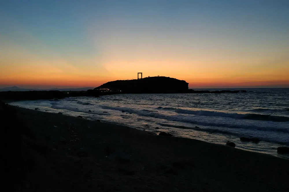 Zonsondergang bij de Portara op Naxos met de zee op de voorgrond