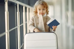 Een klein meisje met een koffer houdt een paspoort vast op een luchthaven