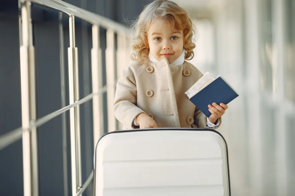 Een klein meisje met een koffer houdt een paspoort vast op een luchthaven