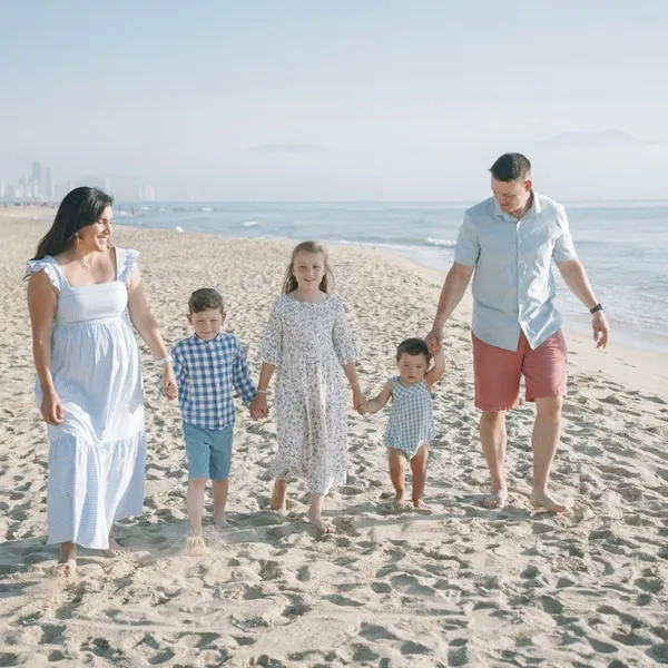 Gezin met kinderen wandelt hand in hand over het strand