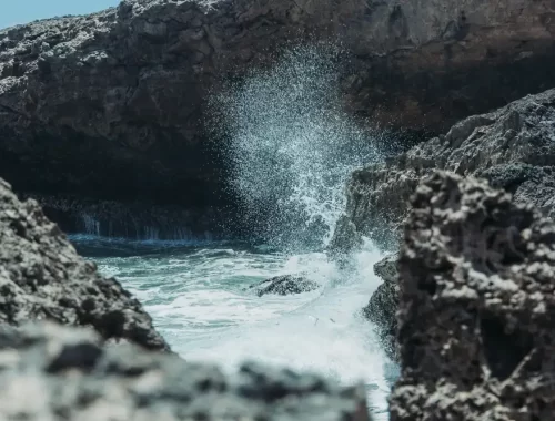 Golven die tussen ruige rotsen opspatten aan de kust van Curaçao
