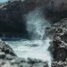 Golven die tussen ruige rotsen opspatten aan de kust van Curaçao