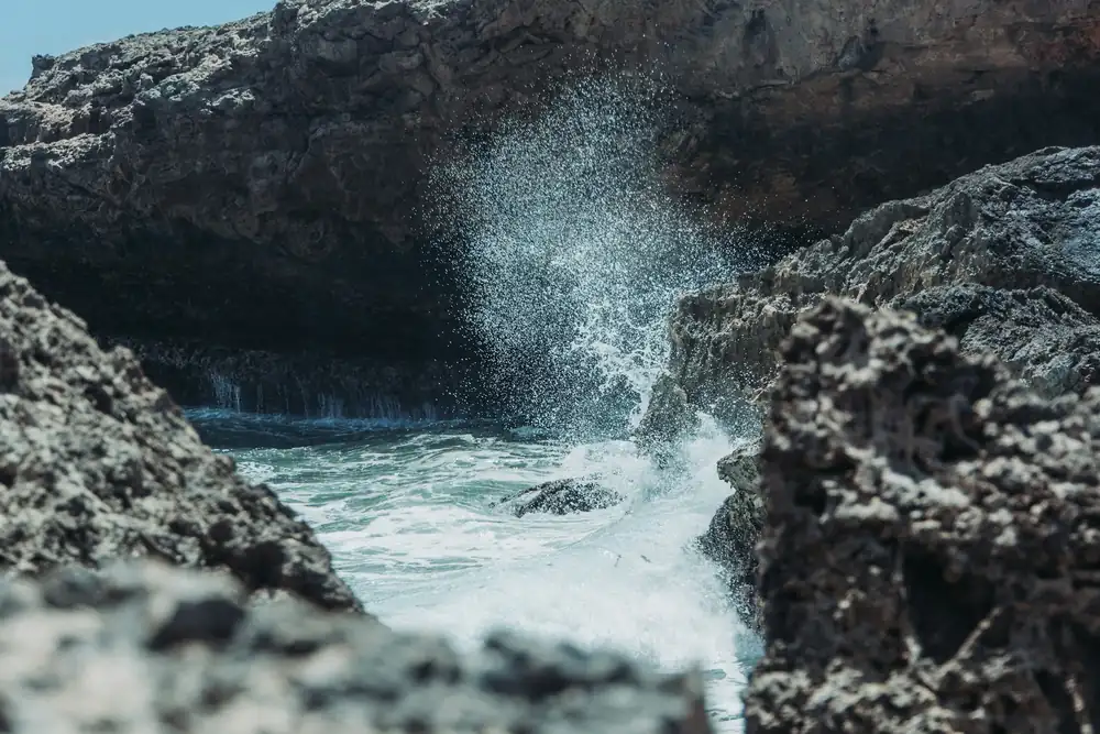Golven die tussen ruige rotsen opspatten aan de kust van Curaçao