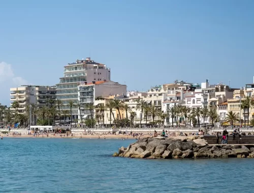 Strand en witte huizen met palmbomen aan de boulevard van Sitges