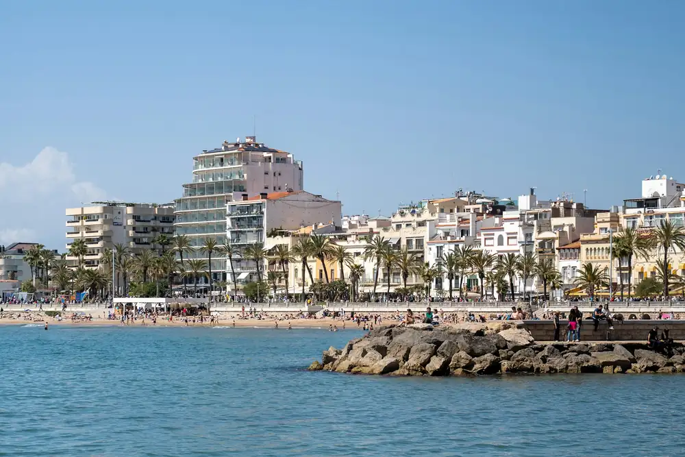 Strand en witte huizen met palmbomen aan de boulevard van Sitges