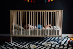 Een peuter slaapt rustig in een houten ledikantje in een donkere kamer