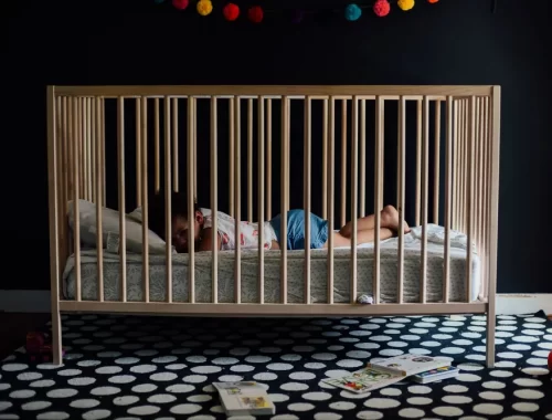 Een peuter slaapt rustig in een houten ledikantje in een donkere kamer