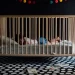 Een peuter slaapt rustig in een houten ledikantje in een donkere kamer